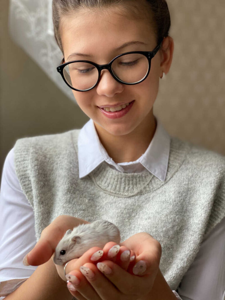 A girl holding a hamster in her hands.